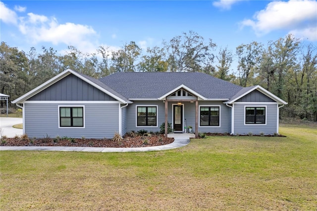 view of front of house featuring a shingled roof, a front lawn, and board and batten siding