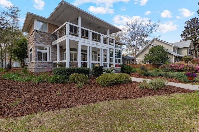 back of property with stone siding and a balcony