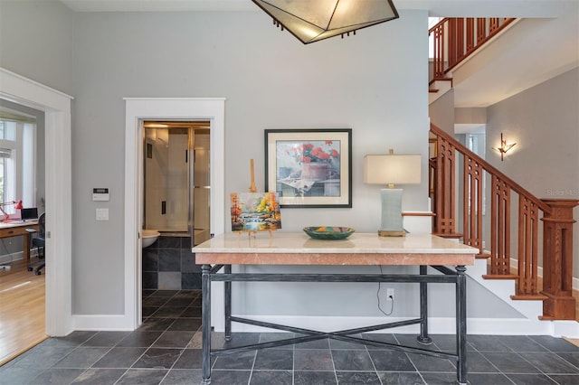 interior space with stairway, a towering ceiling, and baseboards