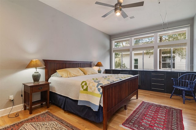 bedroom featuring light wood finished floors, visible vents, multiple windows, and baseboards