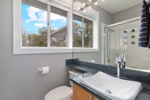 full bath featuring a shower with door, vanity, and toilet