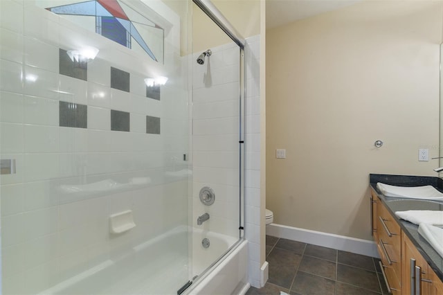 bathroom with double vanity, baseboards, toilet, tile patterned floors, and a sink