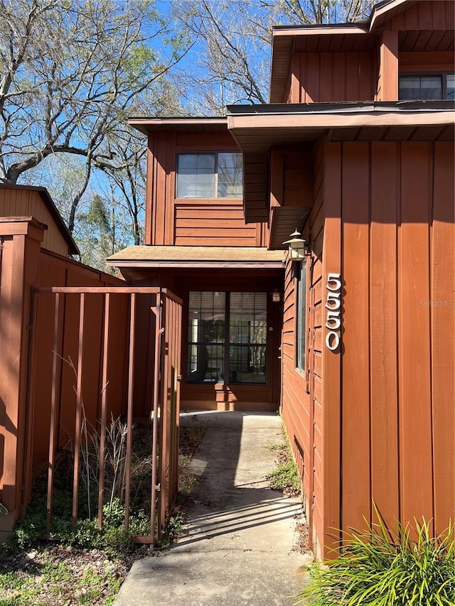 doorway to property with board and batten siding and fence