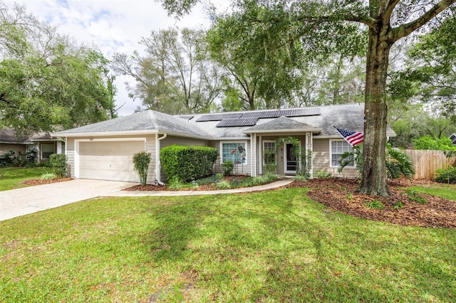 ranch-style house featuring a front lawn, fence, concrete driveway, an attached garage, and solar panels