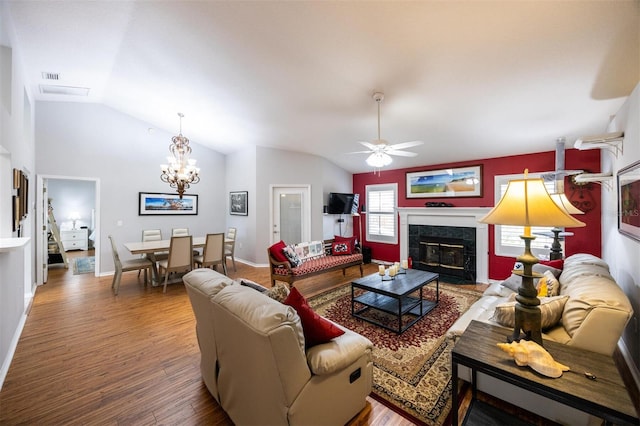 living room with wood finished floors, baseboards, a fireplace, vaulted ceiling, and ceiling fan with notable chandelier