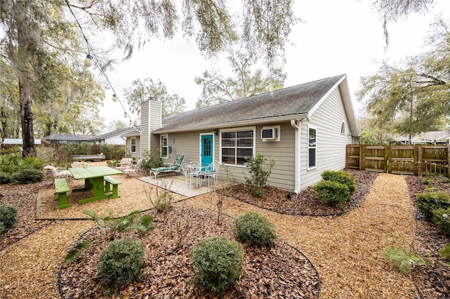 rear view of house with a patio area, a chimney, and fence