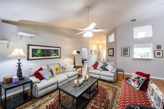 living room with wood finished floors, visible vents, baseboards, lofted ceiling, and ceiling fan