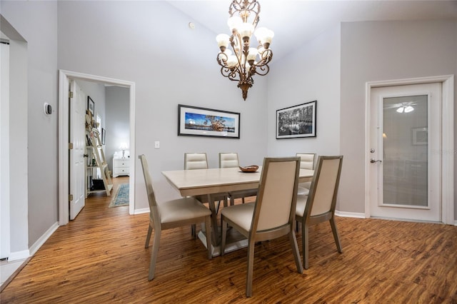 dining area featuring baseboards, a notable chandelier, wood finished floors, and a towering ceiling