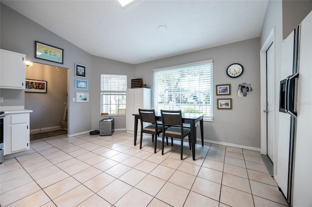 dining room featuring light tile patterned floors, baseboards, and vaulted ceiling