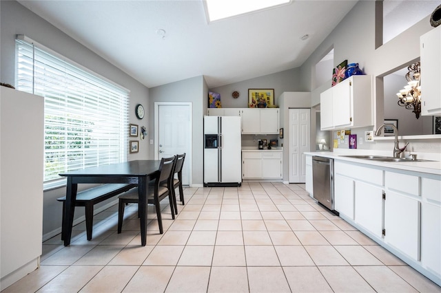 kitchen with light tile patterned floors, white refrigerator with ice dispenser, freestanding refrigerator, stainless steel dishwasher, and a sink