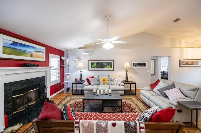 living area featuring visible vents, baseboards, a fireplace, lofted ceiling, and ceiling fan