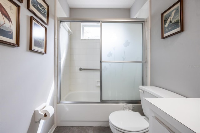 bathroom featuring combined bath / shower with glass door, toilet, and vanity