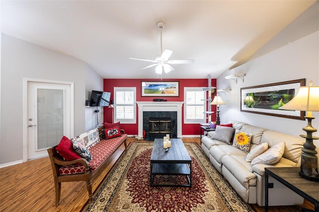 living area featuring a fireplace, vaulted ceiling, wood finished floors, and ceiling fan