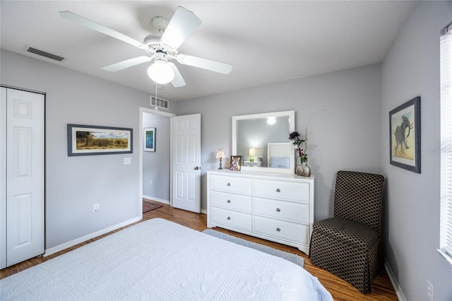 bedroom featuring ceiling fan, wood finished floors, visible vents, and baseboards