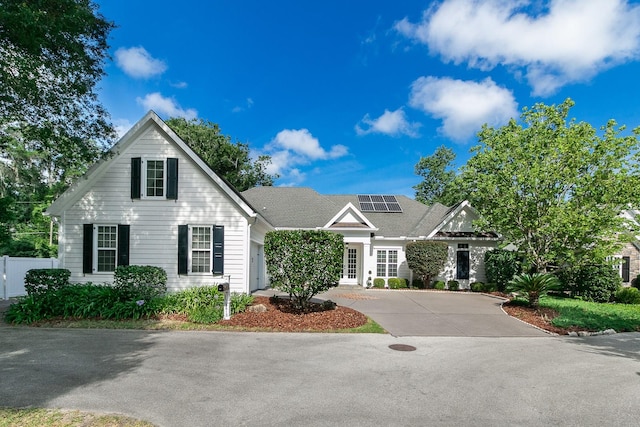 view of front facade with roof mounted solar panels and driveway