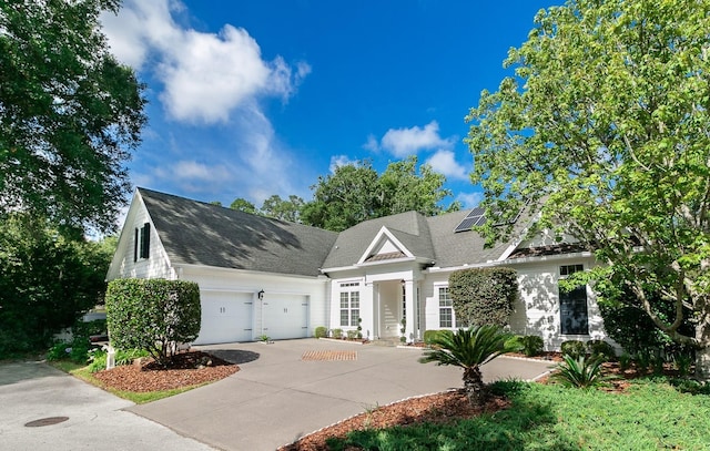 view of front of house featuring driveway, a shingled roof, a garage, and roof mounted solar panels