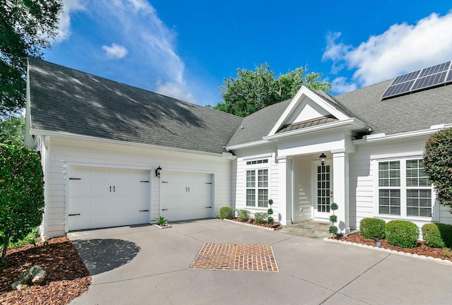 view of front of property with driveway, an attached garage, metal roof, and roof with shingles