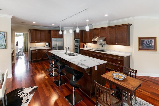 kitchen with dark wood-type flooring, a sink, under cabinet range hood, and built in appliances