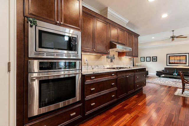 kitchen featuring recessed lighting, under cabinet range hood, dark wood-type flooring, ornamental molding, and appliances with stainless steel finishes