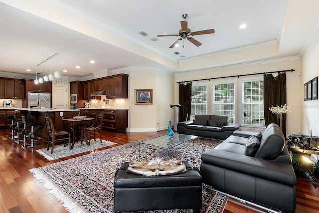 living area featuring dark wood-style flooring, a raised ceiling, and crown molding