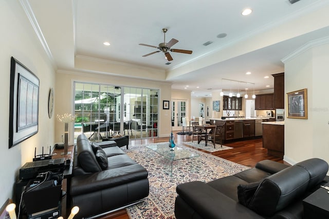 living room featuring a tray ceiling, dark wood-style flooring, and crown molding