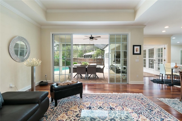 living area with baseboards, wood finished floors, and ornamental molding