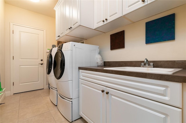 clothes washing area with cabinet space, a sink, washer and clothes dryer, and light tile patterned floors