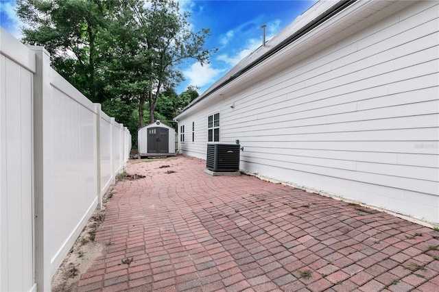 view of patio with a shed, an outdoor structure, a fenced backyard, and central air condition unit