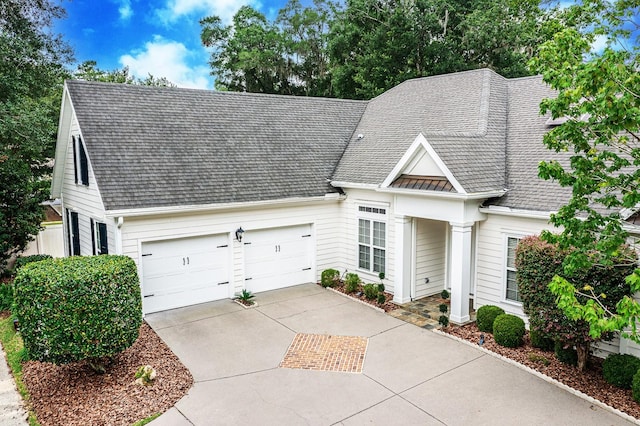 view of front facade featuring concrete driveway, a shingled roof, and an attached garage