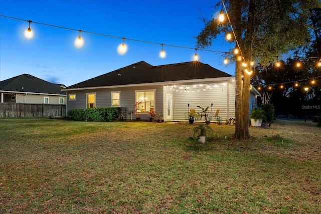 rear view of property with a lawn and fence
