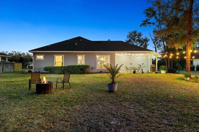 back of house with a lawn and an outdoor fire pit