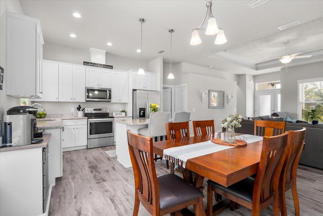 dining room featuring a ceiling fan, visible vents, light wood-type flooring, a tray ceiling, and recessed lighting