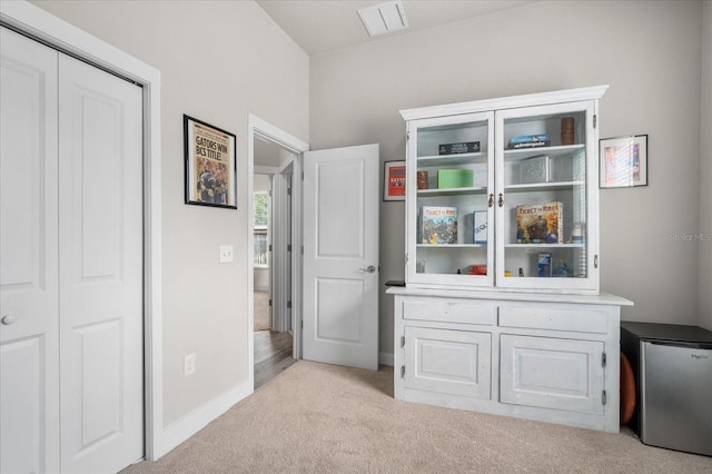 bedroom featuring light colored carpet, freestanding refrigerator, baseboards, visible vents, and a closet