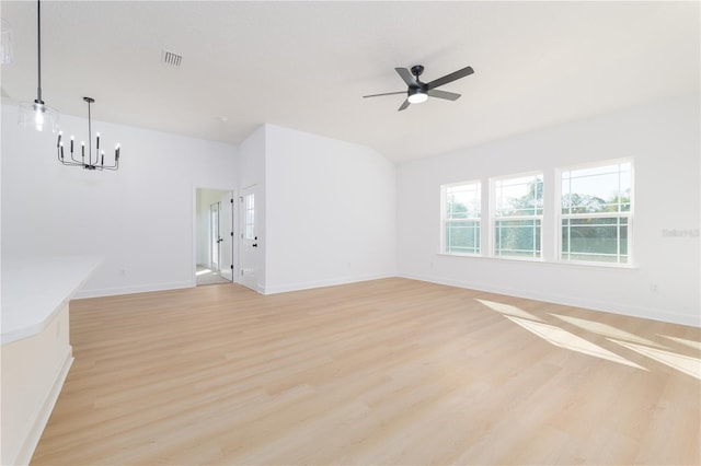 spare room with light wood finished floors, baseboards, visible vents, vaulted ceiling, and ceiling fan with notable chandelier