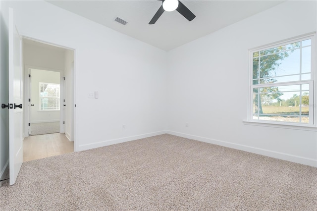 unfurnished room with baseboards, visible vents, and light colored carpet