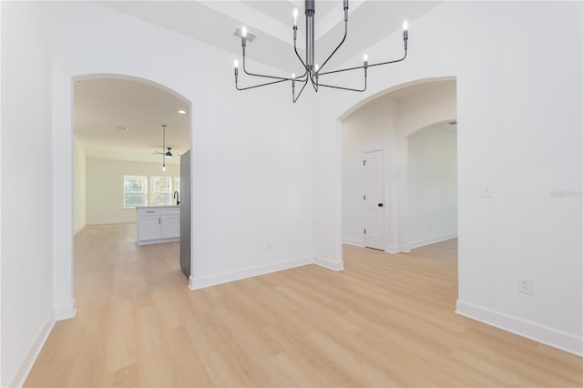 unfurnished dining area featuring arched walkways, recessed lighting, light wood-style flooring, and baseboards