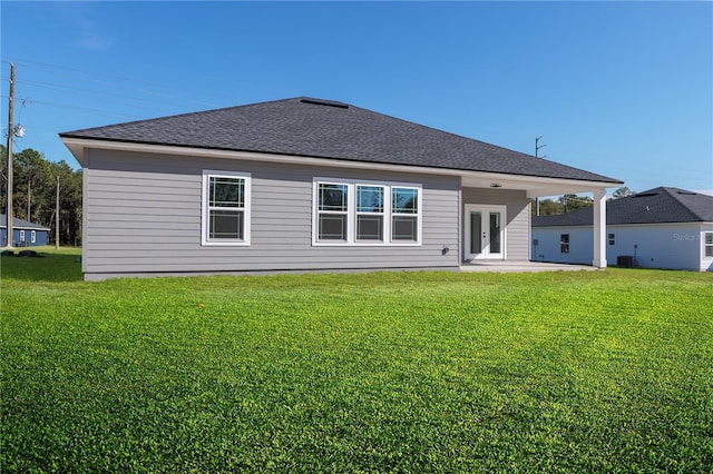 rear view of house with french doors, roof with shingles, a lawn, and a patio