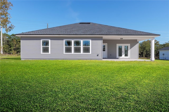 back of property with a yard, roof with shingles, a patio area, and french doors