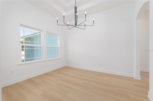 unfurnished room featuring light wood-type flooring, arched walkways, and baseboards