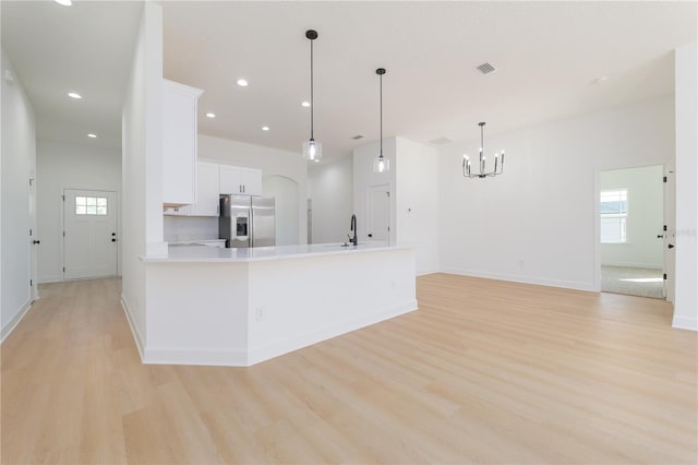 kitchen featuring light wood-style floors, stainless steel fridge, visible vents, and white cabinets