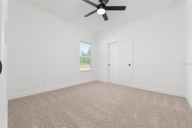 carpeted empty room featuring baseboards and a ceiling fan