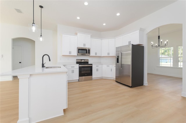 kitchen with a peninsula, a sink, visible vents, light wood-style floors, and appliances with stainless steel finishes