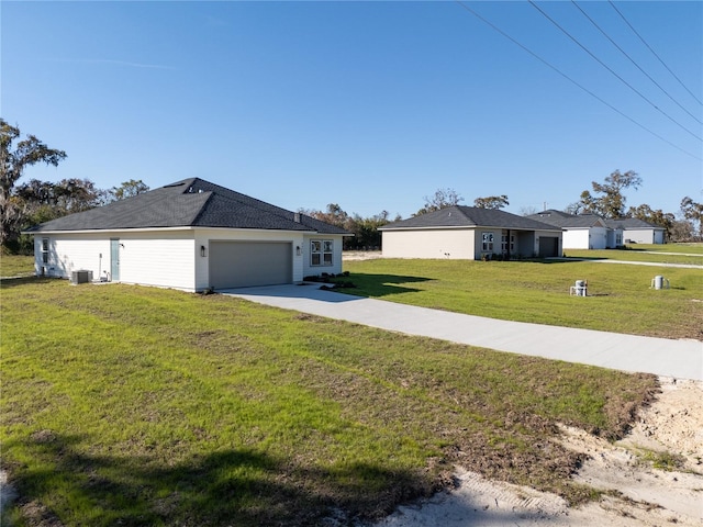 view of side of property with an attached garage, a yard, cooling unit, and concrete driveway