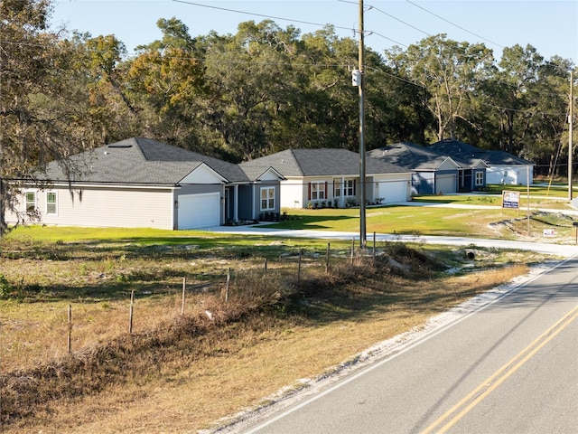 ranch-style house with driveway, a garage, fence, and a front lawn