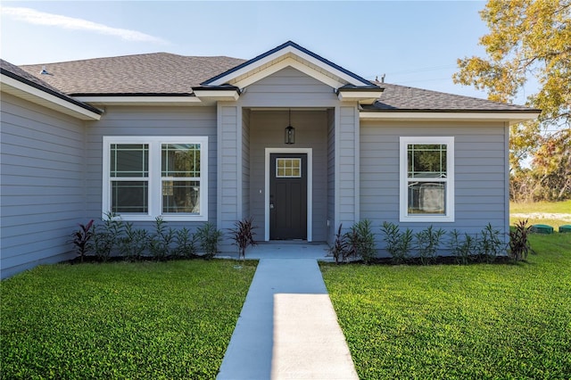 property entrance with a shingled roof and a lawn