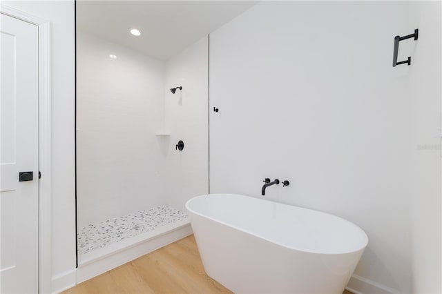 bathroom with recessed lighting, a tile shower, a freestanding bath, and wood finished floors