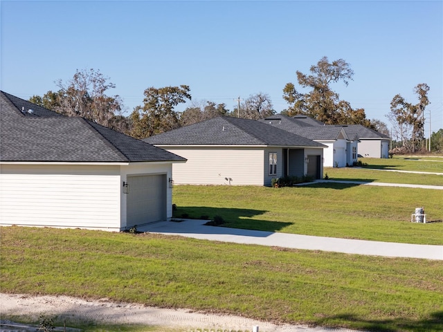 view of front of home featuring a garage, concrete driveway, a shingled roof, and a front yard