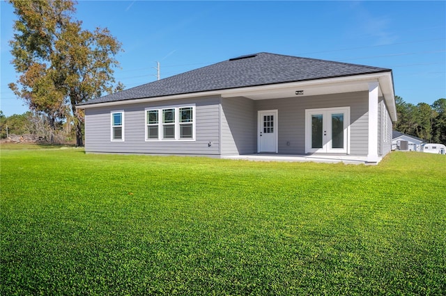 rear view of house with a patio, french doors, a lawn, and roof with shingles