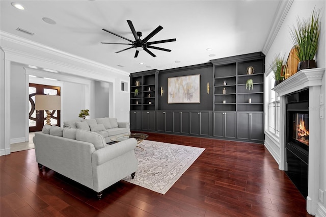 living room with crown molding, visible vents, hardwood / wood-style floors, and a glass covered fireplace