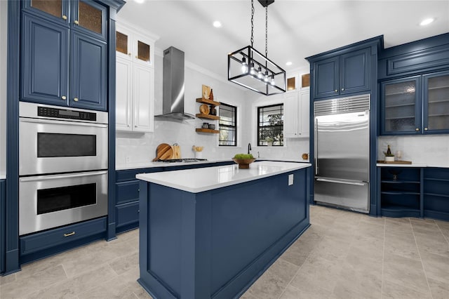 kitchen featuring decorative backsplash, wall chimney exhaust hood, blue cabinets, stainless steel appliances, and light countertops